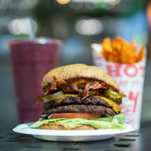 A double cheeseburger with bacon and jalapeños, sweet potato fries, and a berry smoothie.